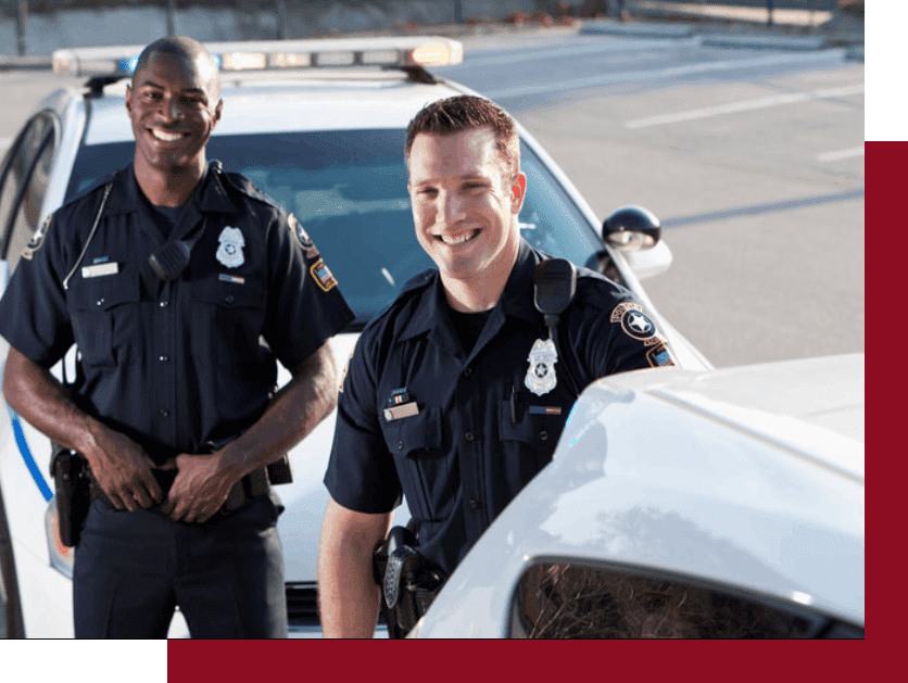 Two police officers standing next to a white car.